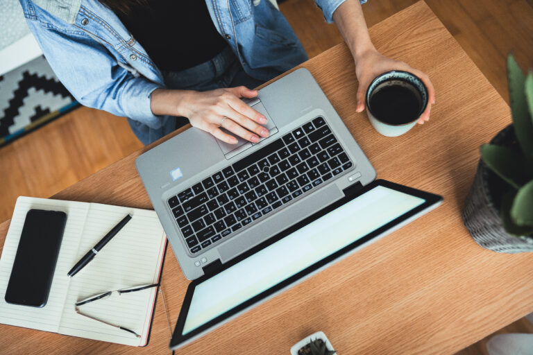 high-angle-view-woman-sitting-desk-working-laptop-while-holding-coffee-mug